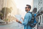 Homme qui regarde une carte lors de son voyage avec un sac à dos